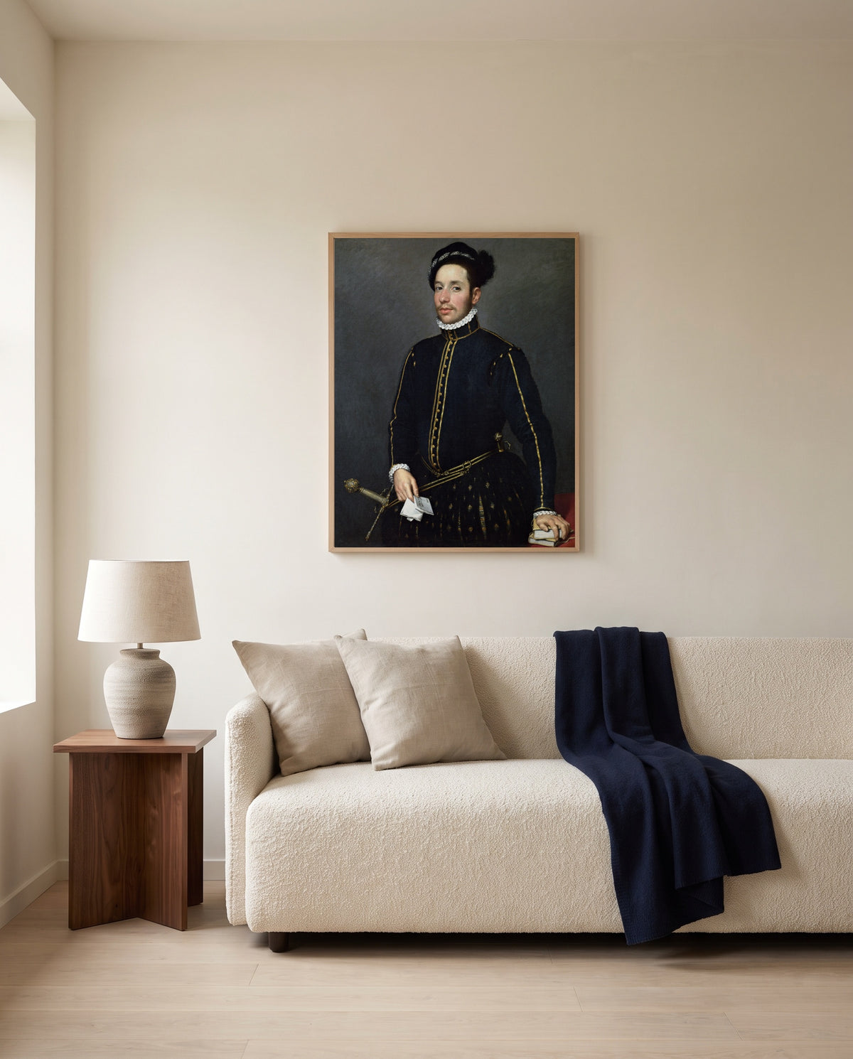 Left-Handed Gentleman by Giovanni Battista Moroni framed in natural oak above a cream sofa in a warm living room