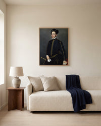 Left-Handed Gentleman by Giovanni Battista Moroni framed in natural oak above a cream sofa in a warm living room