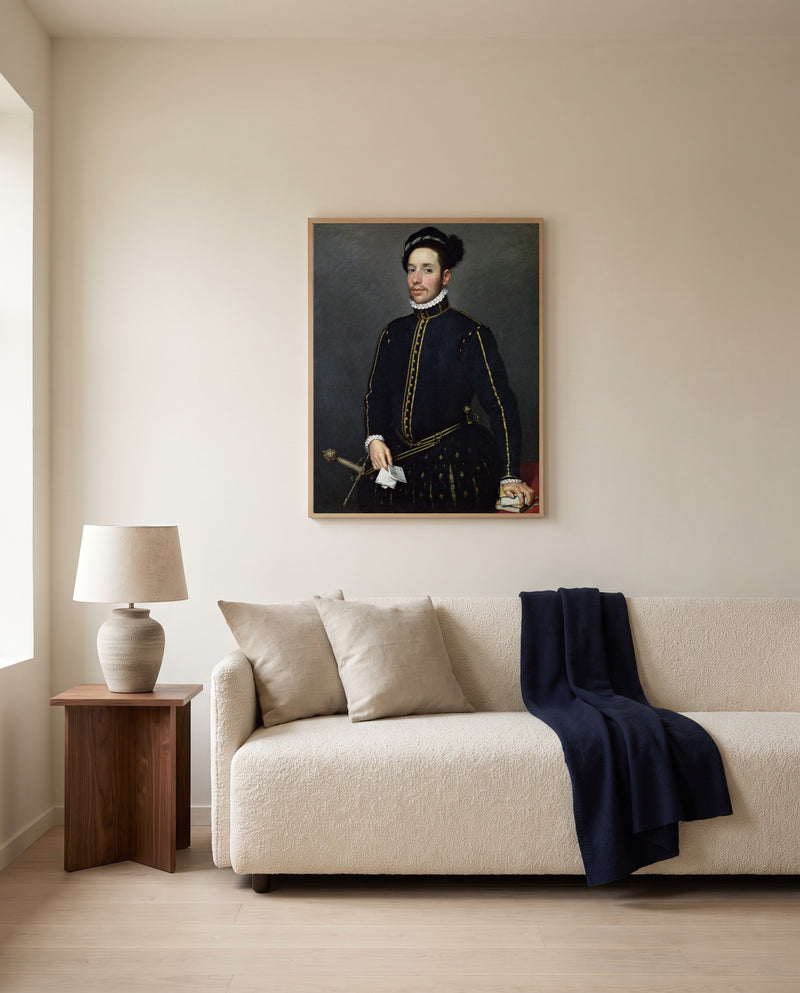 Left-Handed Gentleman by Giovanni Battista Moroni framed in natural oak above a cream sofa in a warm living room