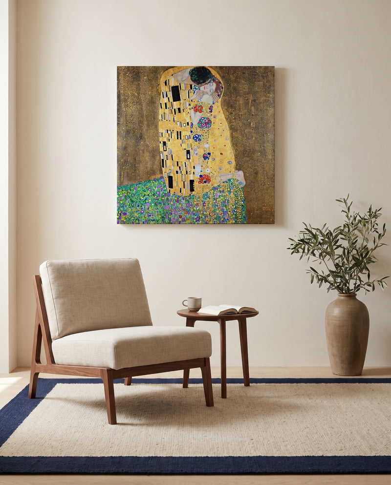 The Kiss by Gustav Klimt as a stretched canvas above a linen lounge chair in a reading corner