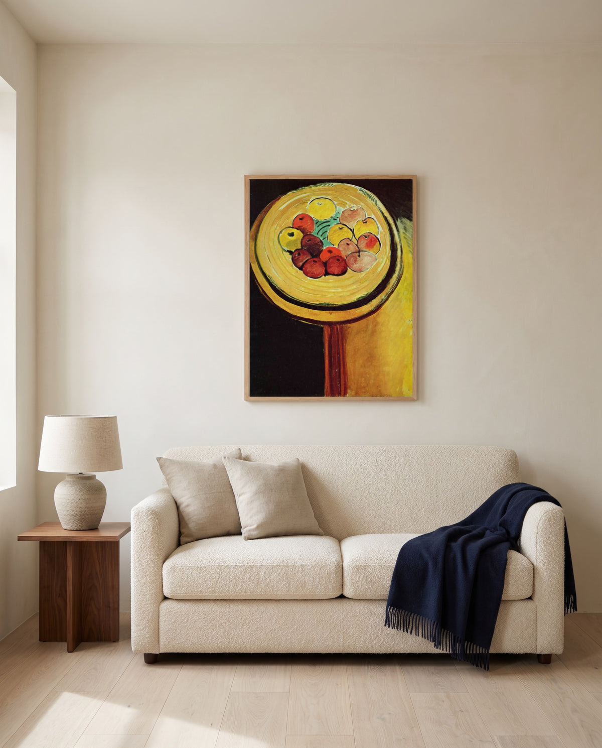 Apples by Henri Matisse framed in natural oak above a cream sofa in a warm living room