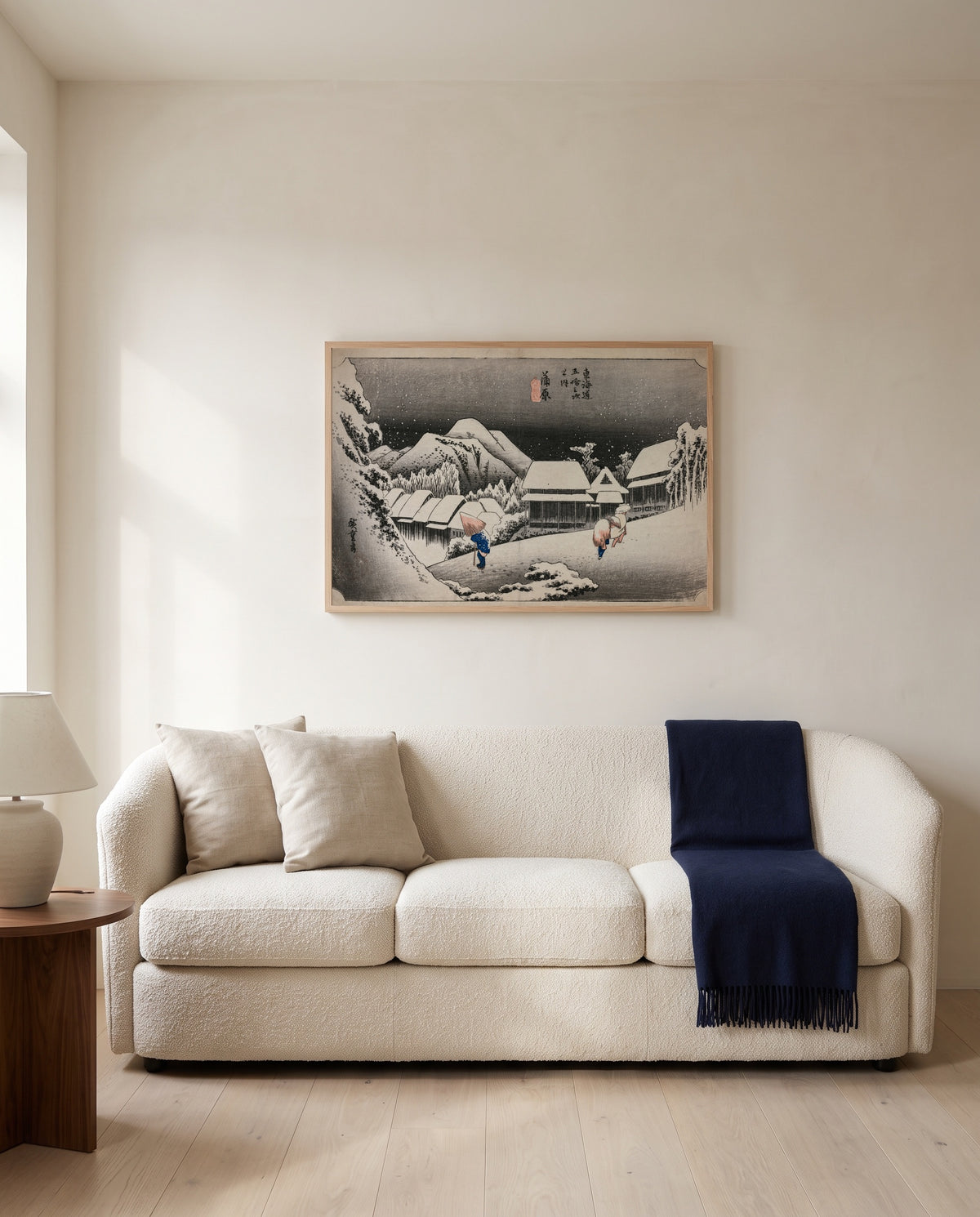 Evening Snow at Kambara by Utagawa Hiroshige framed in natural oak above a cream sofa in a warm living room