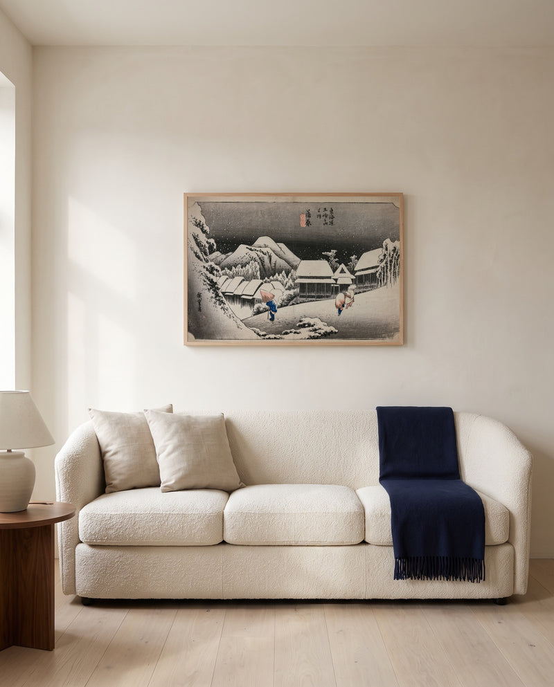 Evening Snow at Kambara by Utagawa Hiroshige framed in natural oak above a cream sofa in a warm living room
