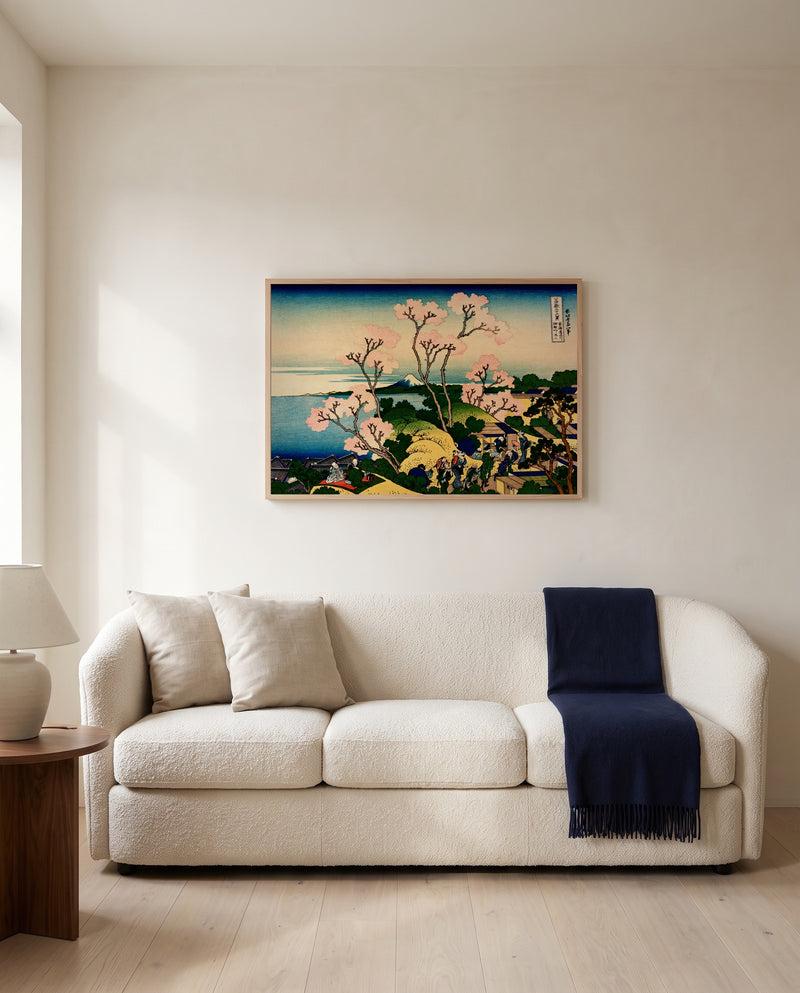 Goten Hill at Shinagawa by Katsushika Hokusai framed in natural oak above a cream sofa in a warm living room