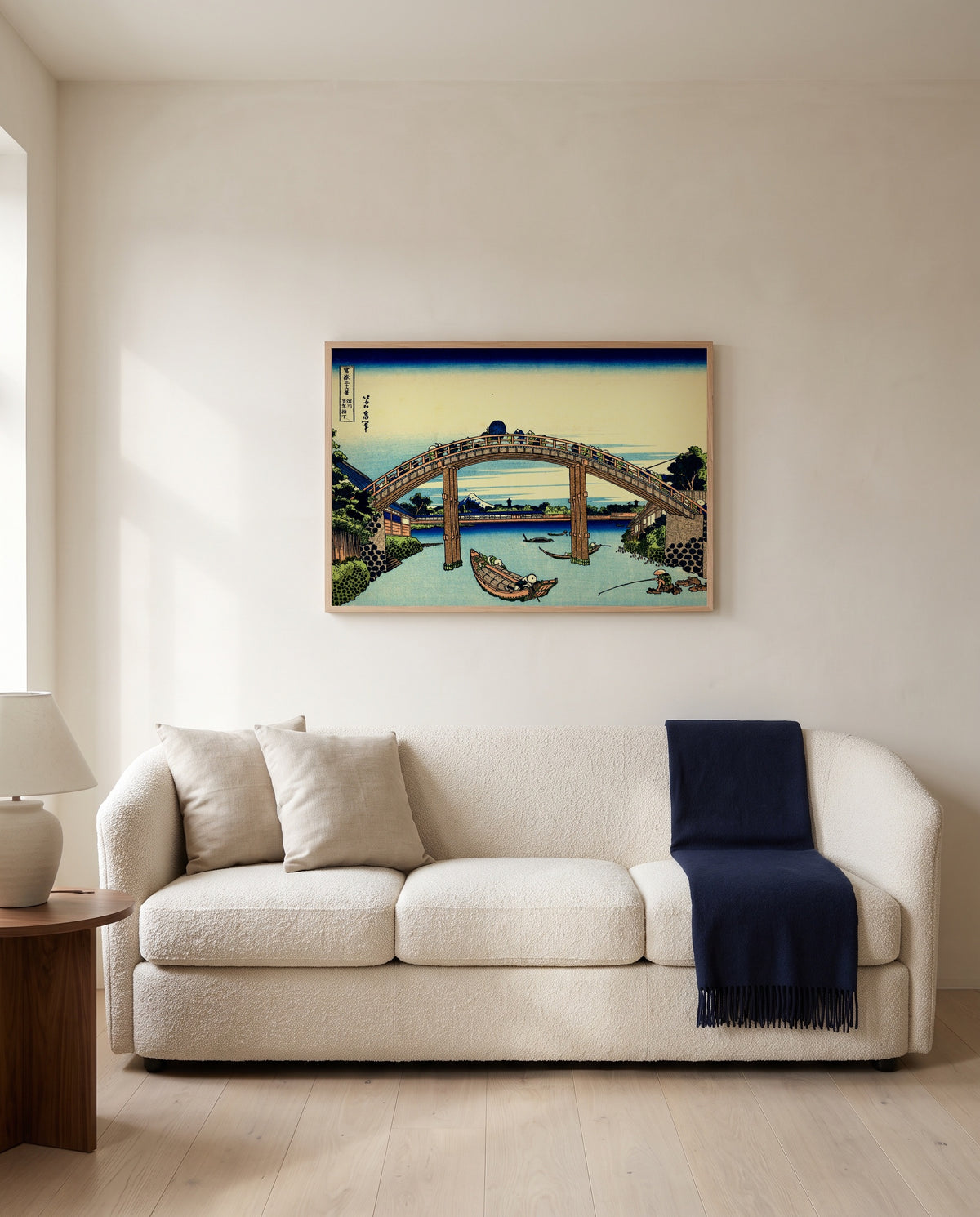 Under Mannen Bridge at Fukagawa by Katsushika Hokusai framed in natural oak above a cream sofa in a warm living room