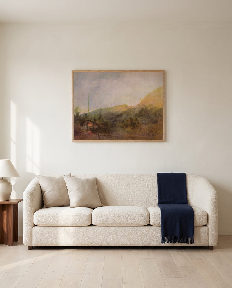 Barge on the River, Sunset by J. M. W. Turner framed in natural oak above a cream sofa in a warm living room