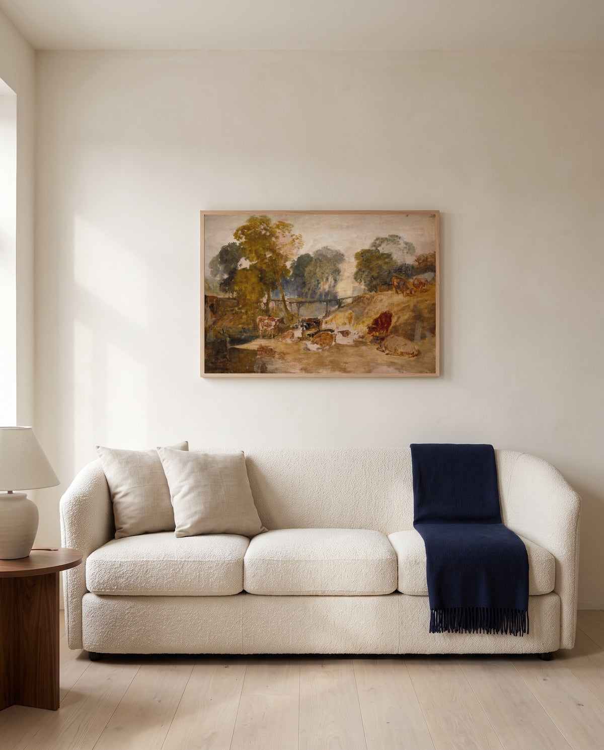 Cows with a Footbridge by J. M. W. Turner framed in natural oak above a cream sofa in a warm living room