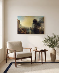 Dido building Carthage by J. M. W. Turner as a stretched canvas above a linen lounge chair in a reading corner