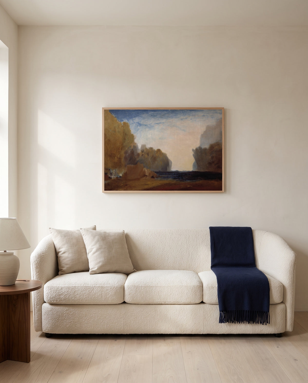 Rocky Bay by J. M. W. Turner framed in natural oak above a cream sofa in a warm living room