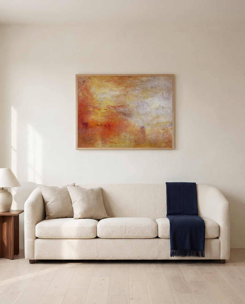 Sun Setting over a Lake by J. M. W. Turner framed in natural oak above a cream sofa in a warm living room
