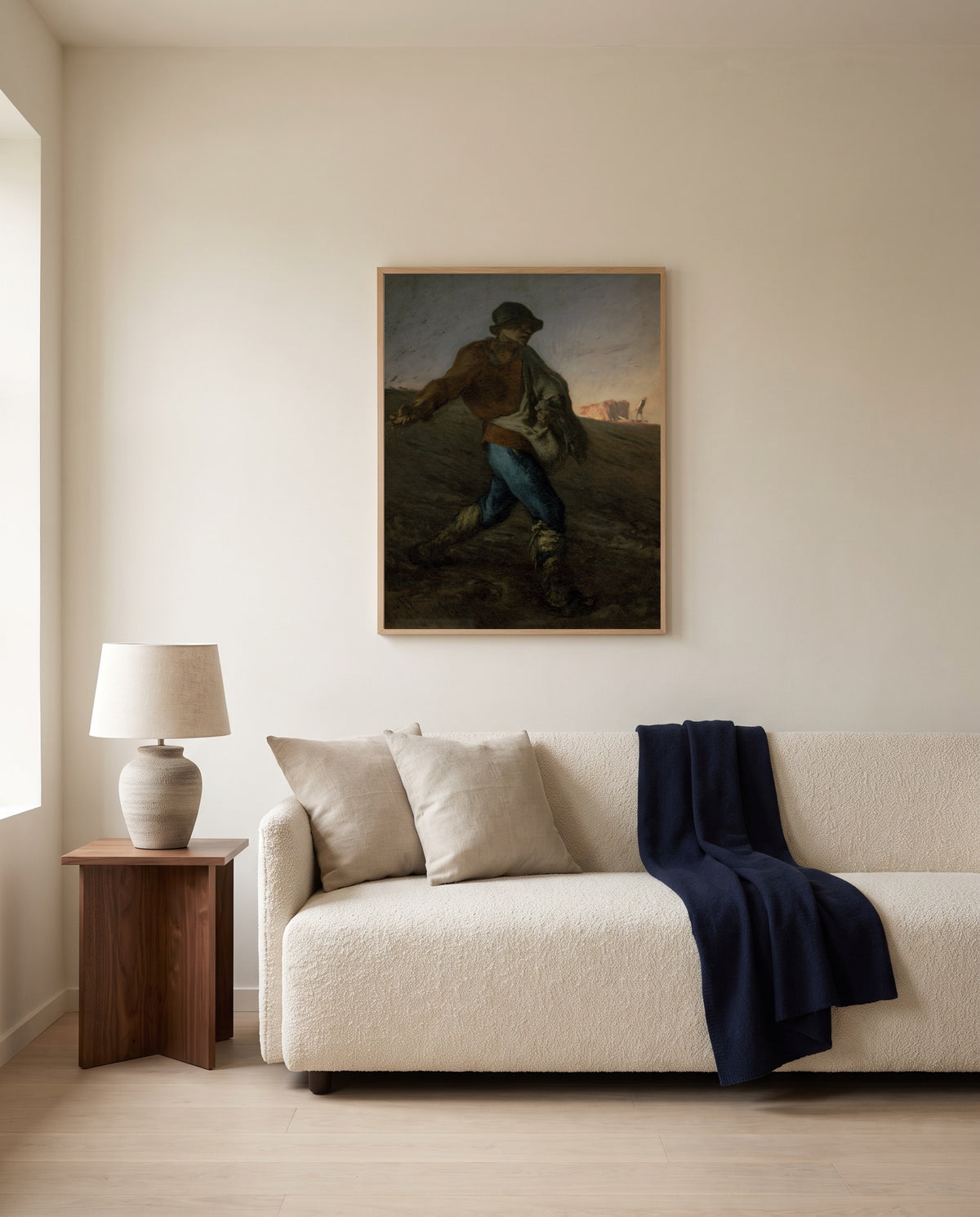 The Sower by Jean-François Millet framed in natural oak above a cream sofa in a warm living room