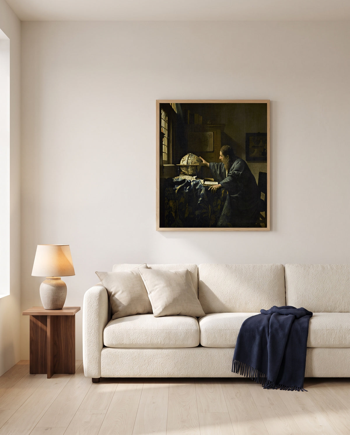 The Astronomer by Johannes Vermeer framed in natural oak above a cream sofa in a warm living room