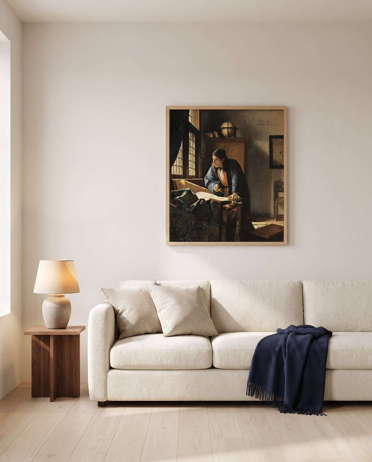 The Geographer by Johannes Vermeer framed in natural oak above a cream sofa in a warm living room