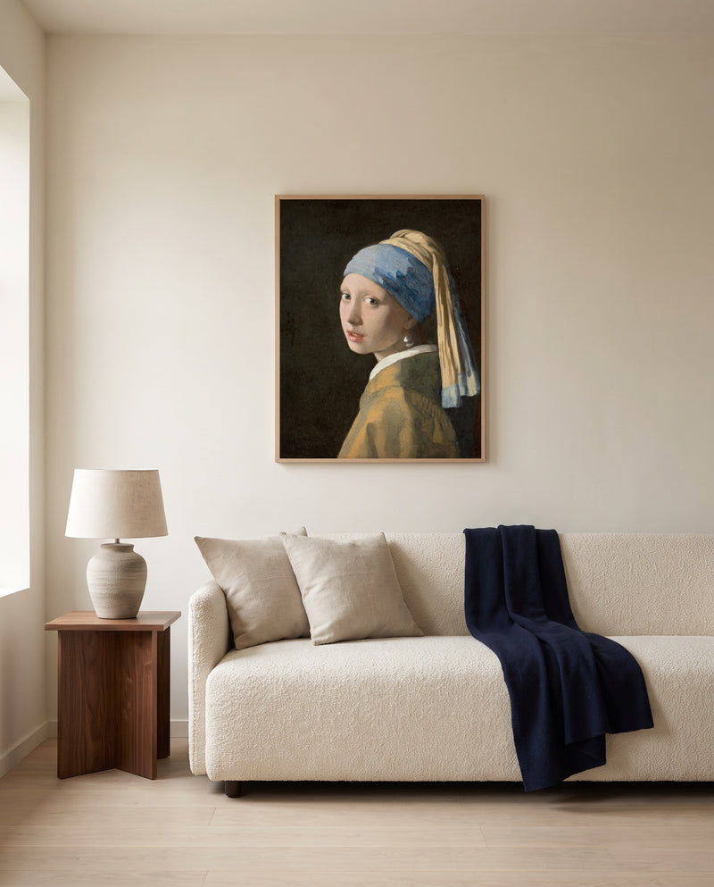 Girl with a Pearl Earring by Johannes Vermeer framed in natural oak above a cream sofa in a warm living room