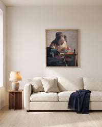 The Lacemaker by Johannes Vermeer framed in natural oak above a cream sofa in a warm living room