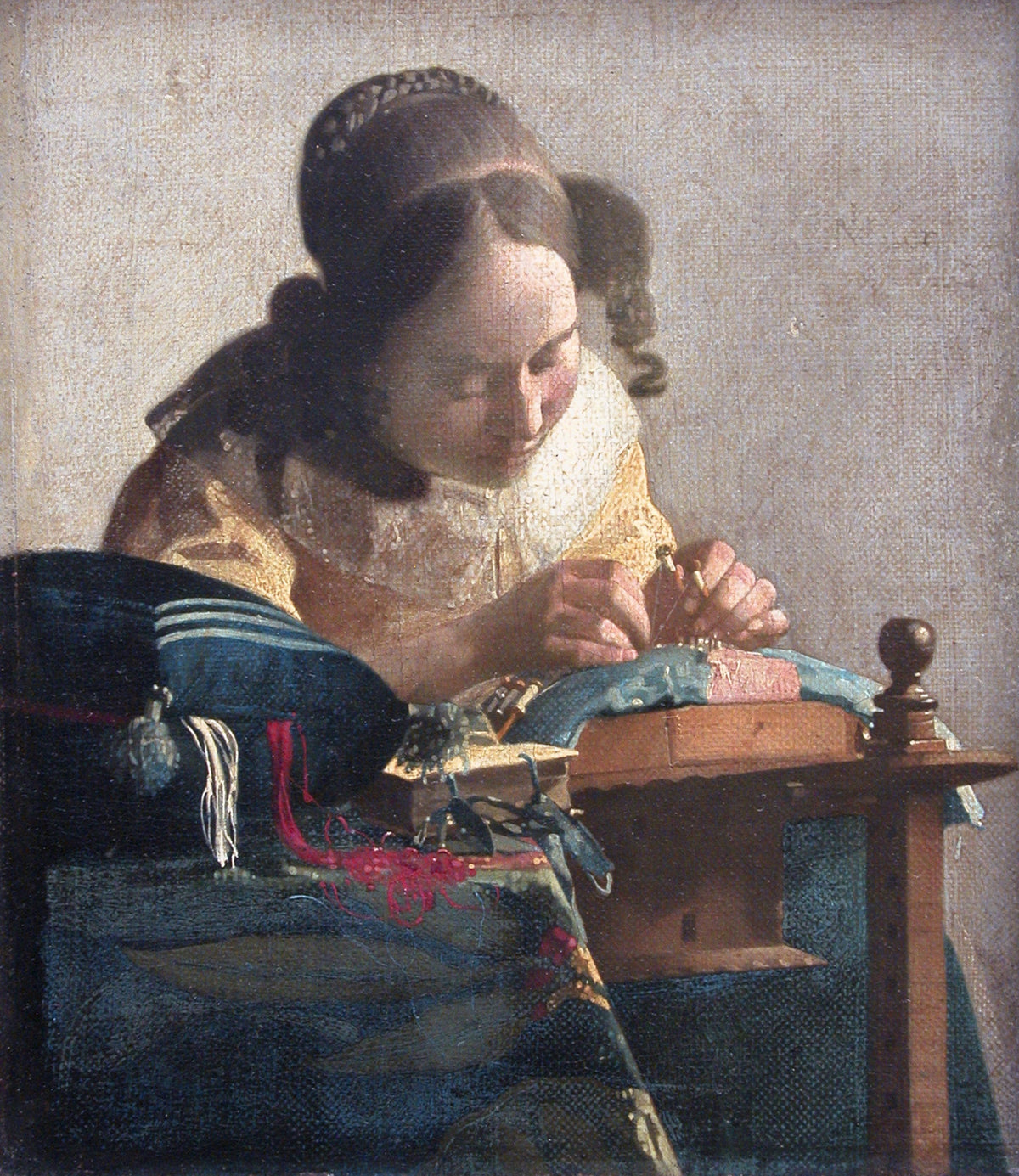 The Lacemaker by Vermeer: a young woman in a yellow bodice bending over her lace pillow, red and white threads spilling out