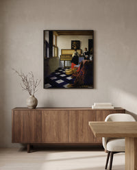 The Music Lesson by Johannes Vermeer in a black frame above a walnut sideboard in a dining room