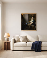 Woman Holding a Balance by Johannes Vermeer framed in natural oak above a cream sofa in a warm living room