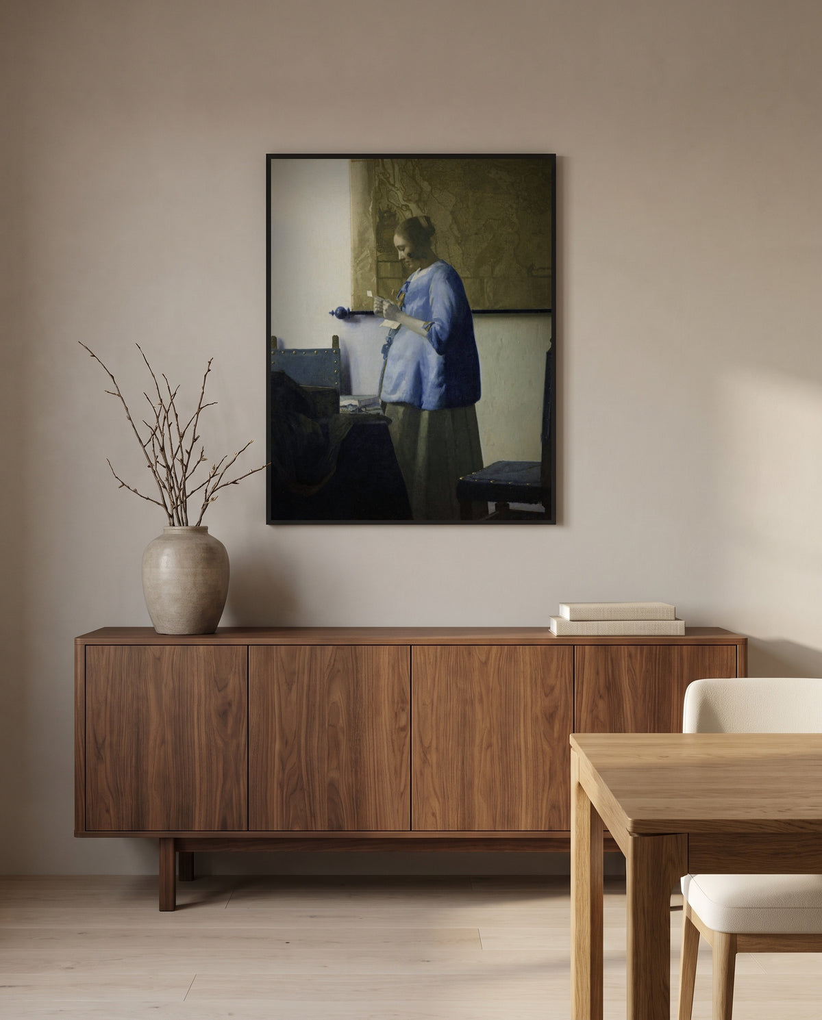 Woman in Blue Reading a Letter by Johannes Vermeer in a black frame above a walnut sideboard in a dining room
