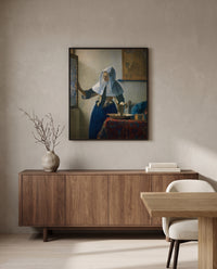 Woman with a Water Pitcher by Johannes Vermeer in a black frame above a walnut sideboard in a dining room