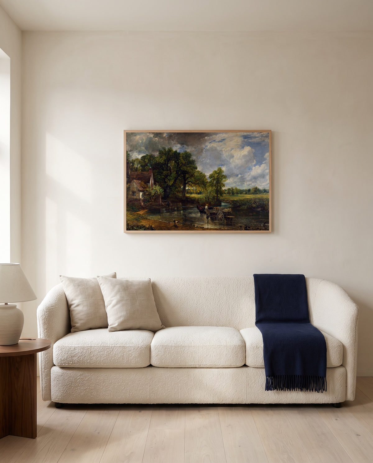 The Hay Wain by John Constable framed in natural oak above a cream sofa in a warm living room