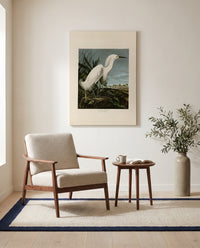 Snowy Heron by John James Audubon as a stretched canvas above a linen lounge chair in a reading corner