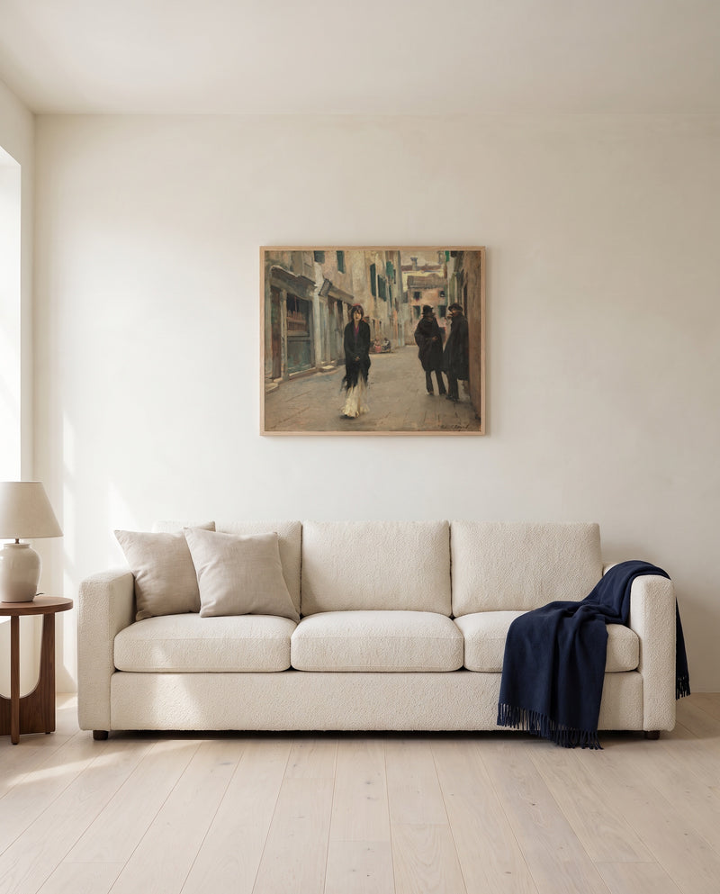 Street in Venice by John Singer Sargent framed in natural oak above a cream sofa in a warm living room