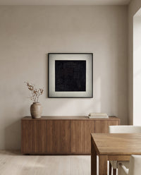 Black Square by Kazimir Malevich in a black frame above a walnut sideboard in a dining room