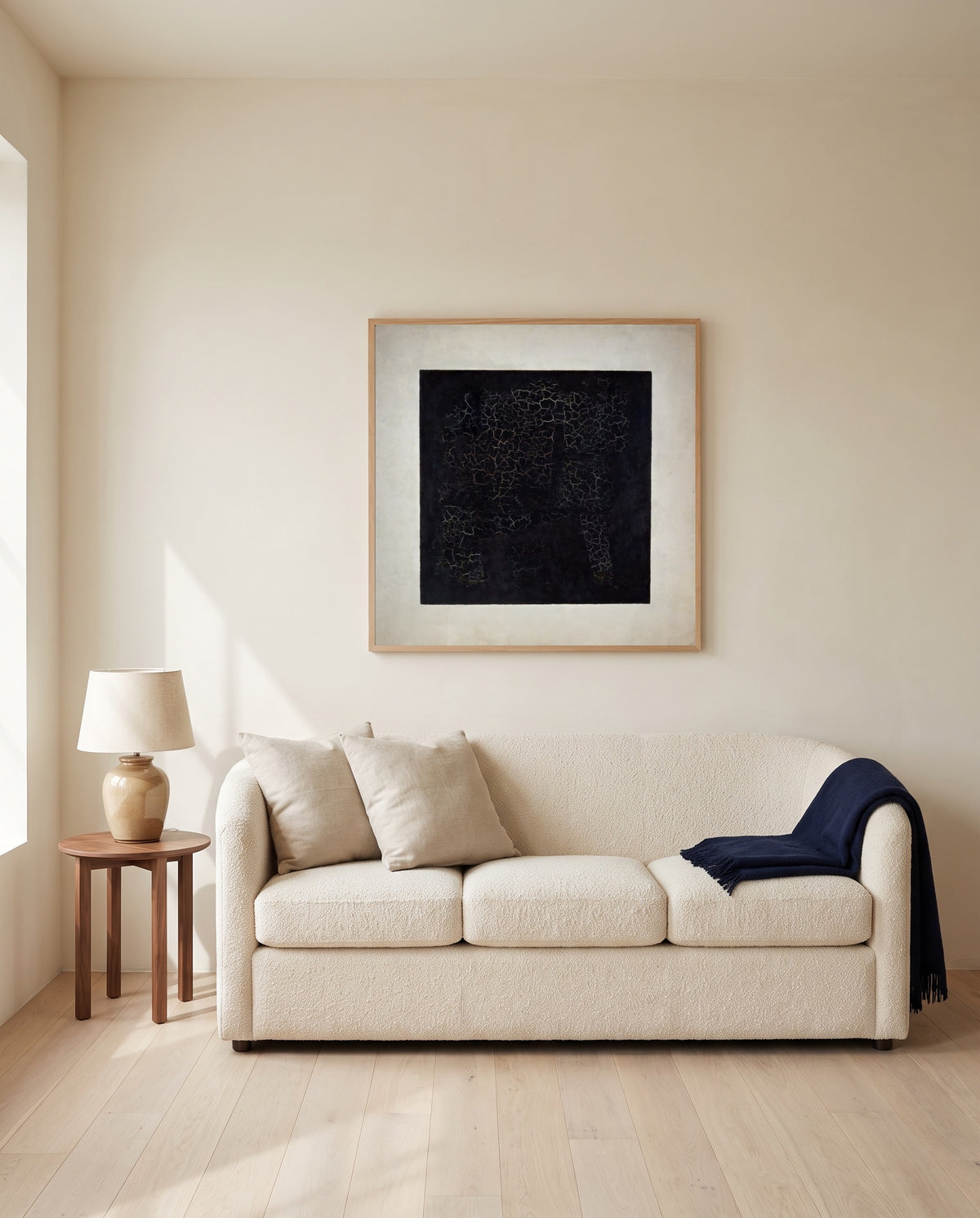 Black Square by Kazimir Malevich framed in natural oak above a cream sofa in a warm living room