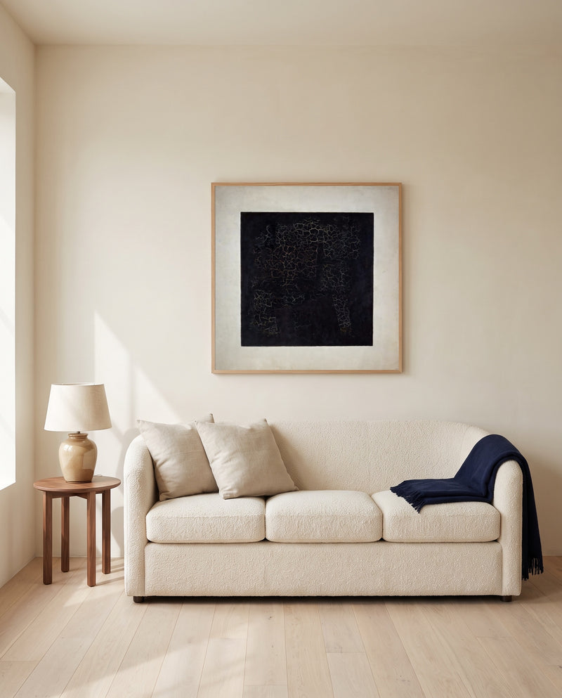 Black Square by Kazimir Malevich framed in natural oak above a cream sofa in a warm living room