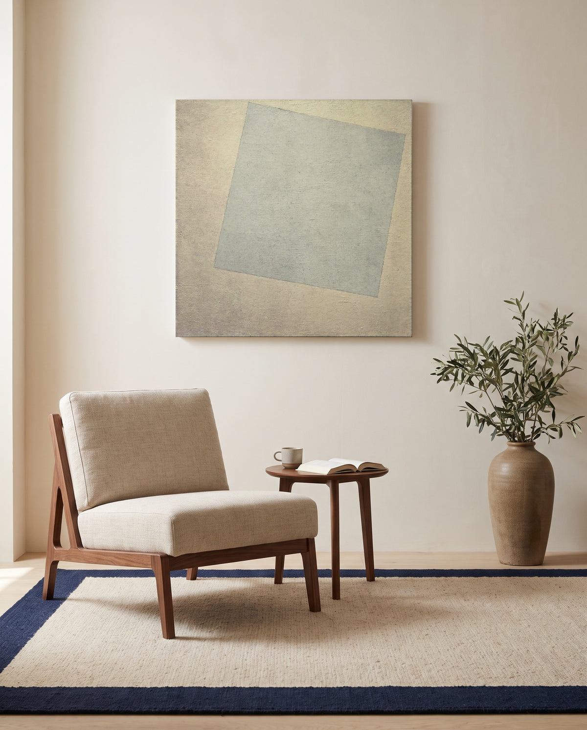 White on White by Kazimir Malevich as a stretched canvas above a linen lounge chair in a reading corner