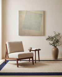 White on White by Kazimir Malevich as a stretched canvas above a linen lounge chair in a reading corner