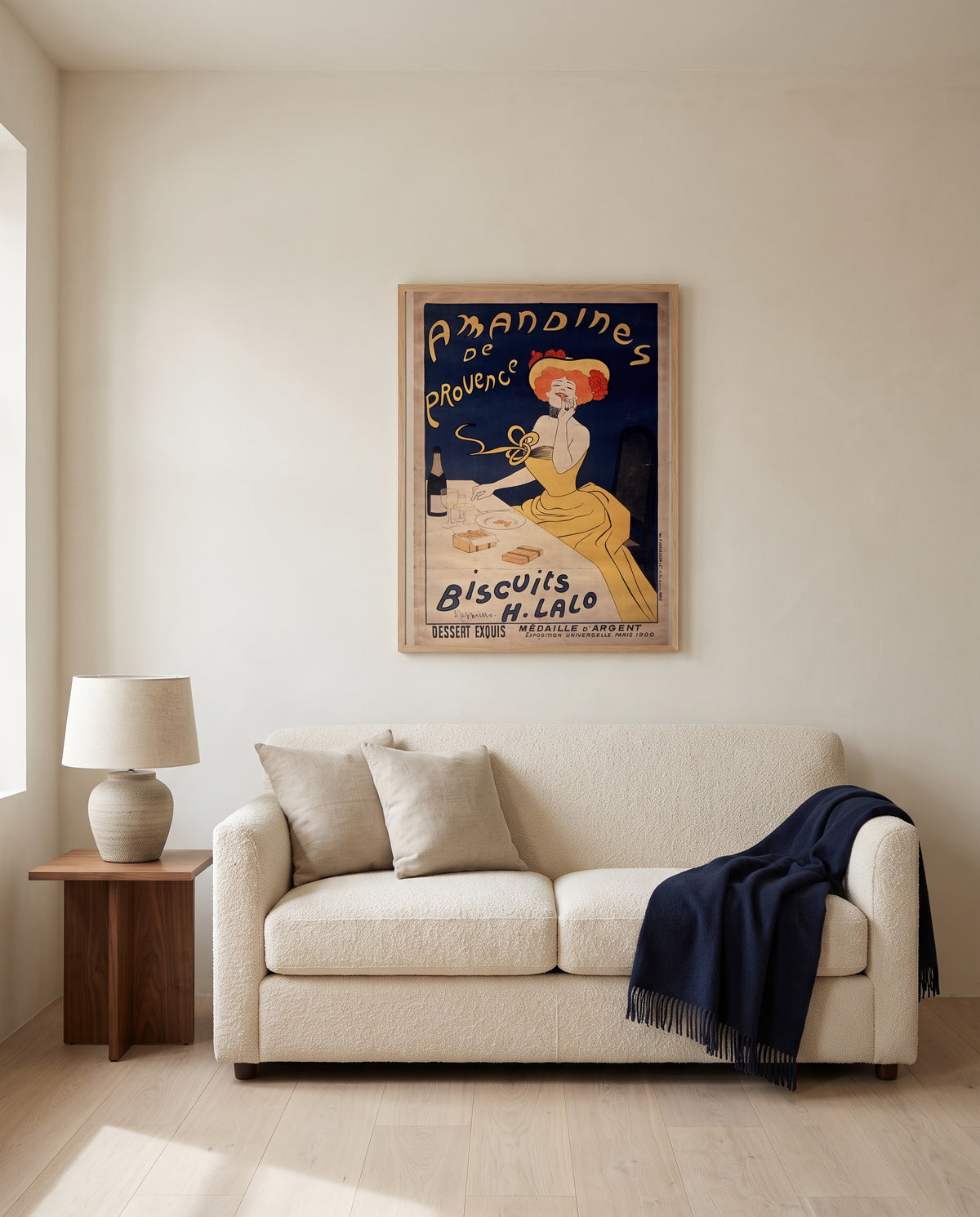 Amandines de Provence by Leonetto Cappiello framed in natural oak above a cream sofa in a warm living room