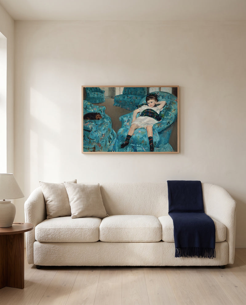 Girl in a Blue Armchair by Mary Cassatt framed in natural oak above a cream sofa in a warm living room