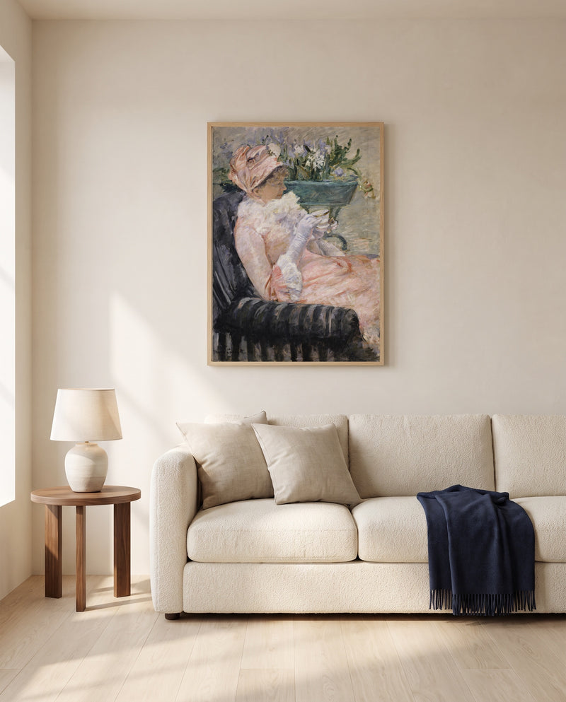 The Cup of Tea by Mary Cassatt framed in natural oak above a cream sofa in a warm living room