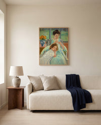 Young Mother Sewing by Mary Cassatt framed in natural oak above a cream sofa in a warm living room