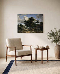 Village Street under Trees by Meindert Hobbema as a stretched canvas above a linen lounge chair in a reading corner