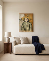 Boy with a Straw Hat by Paul Cézanne framed in natural oak above a cream sofa in a warm living room