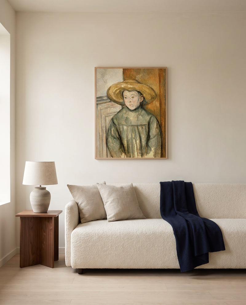 Boy with a Straw Hat by Paul Cézanne framed in natural oak above a cream sofa in a warm living room
