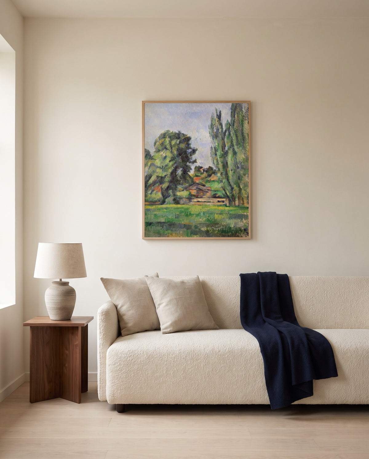 Landscape with Poplars by Paul Cézanne framed in natural oak above a cream sofa in a warm living room