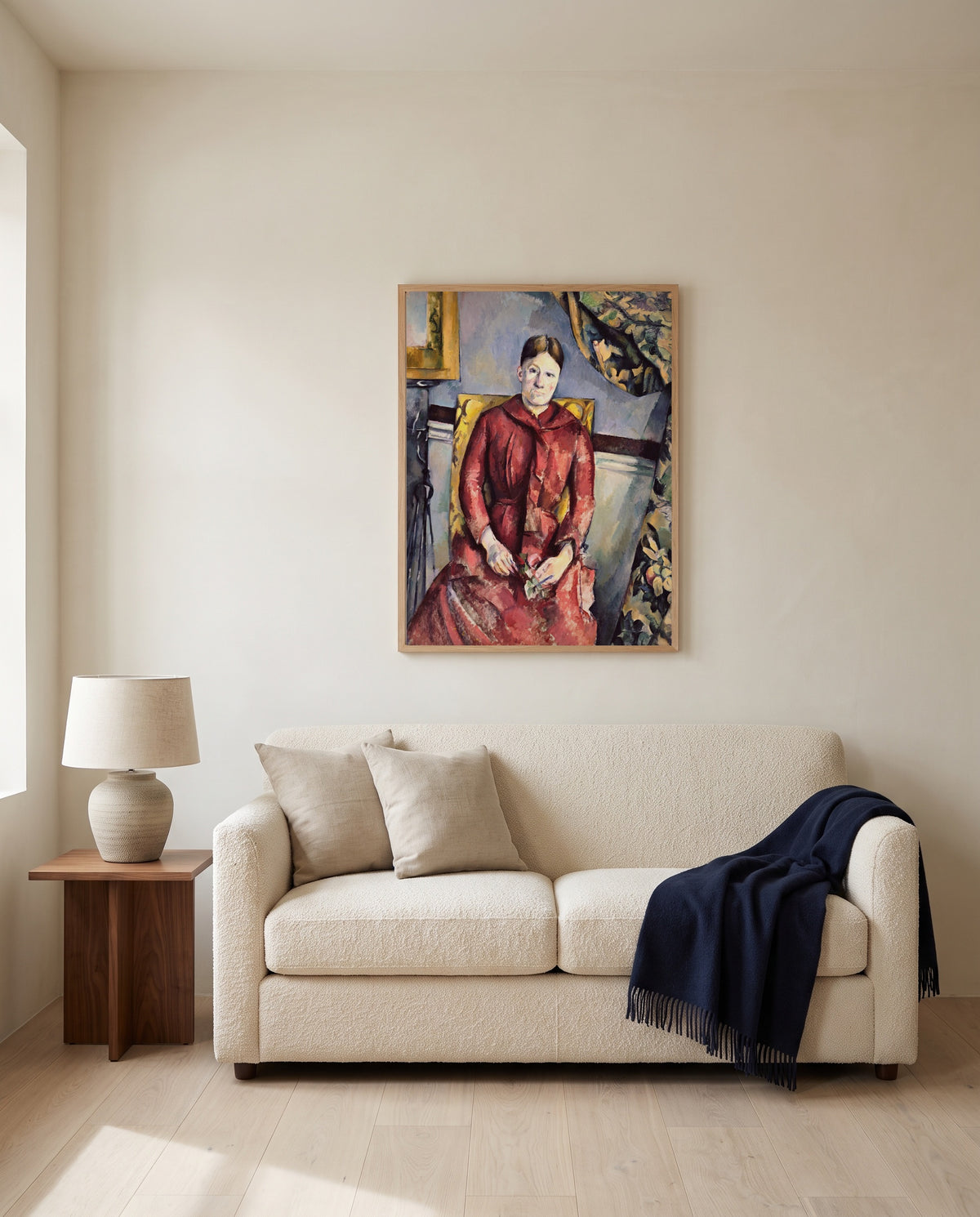 Madame Cézanne in Red by Paul Cézanne framed in natural oak above a cream sofa in a warm living room