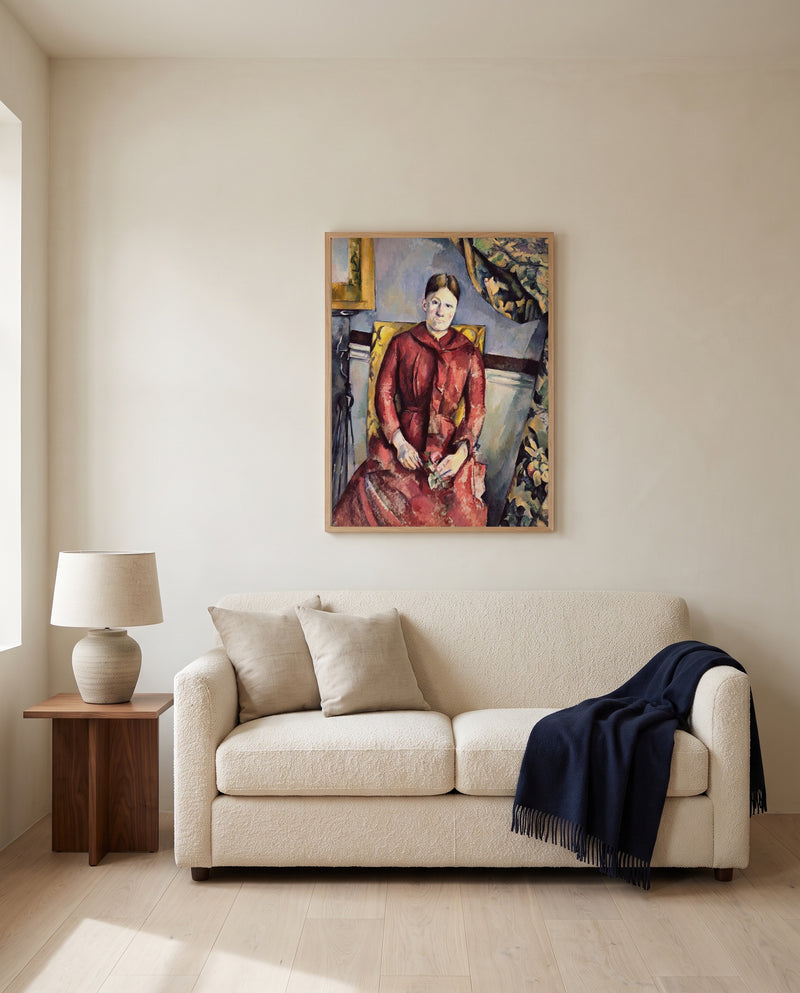 Madame Cézanne in Red by Paul Cézanne framed in natural oak above a cream sofa in a warm living room
