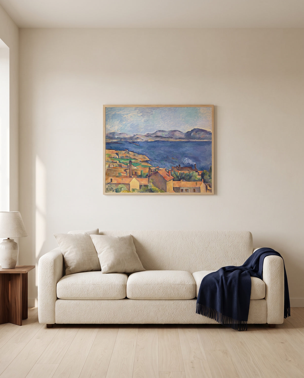 The Bay of Marseille by Paul Cézanne framed in natural oak above a cream sofa in a warm living room
