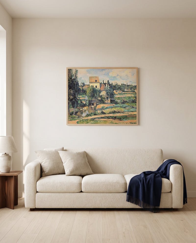 Mill at Pontoise by Paul Cézanne framed in natural oak above a cream sofa in a warm living room