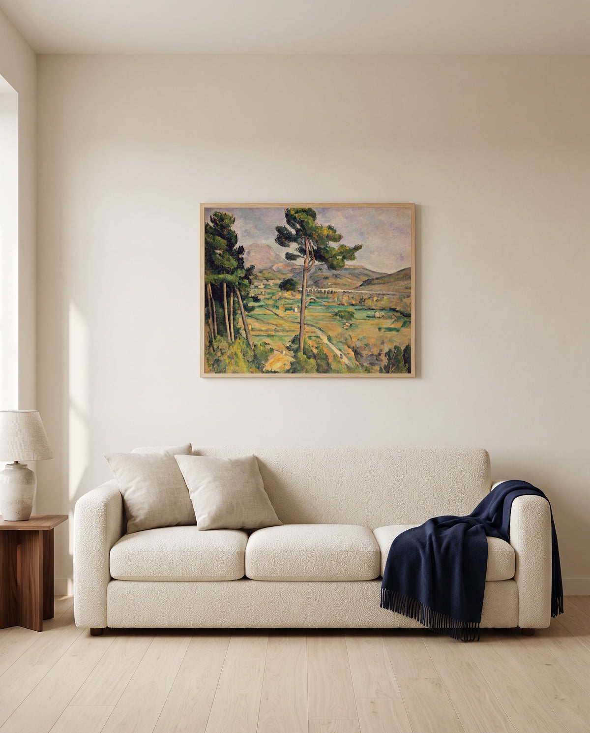 Sainte-Victoire and the Viaduct by Paul Cézanne framed in natural oak above a cream sofa in a warm living room