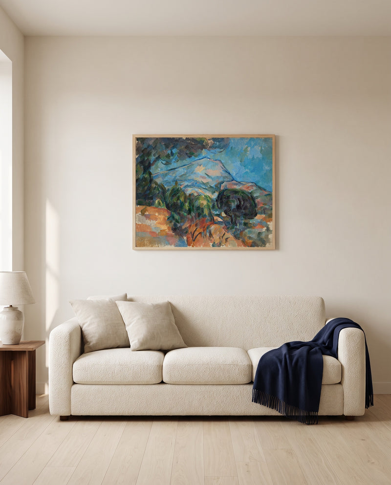 Mount Sainte-Victoire by Paul Cézanne framed in natural oak above a cream sofa in a warm living room