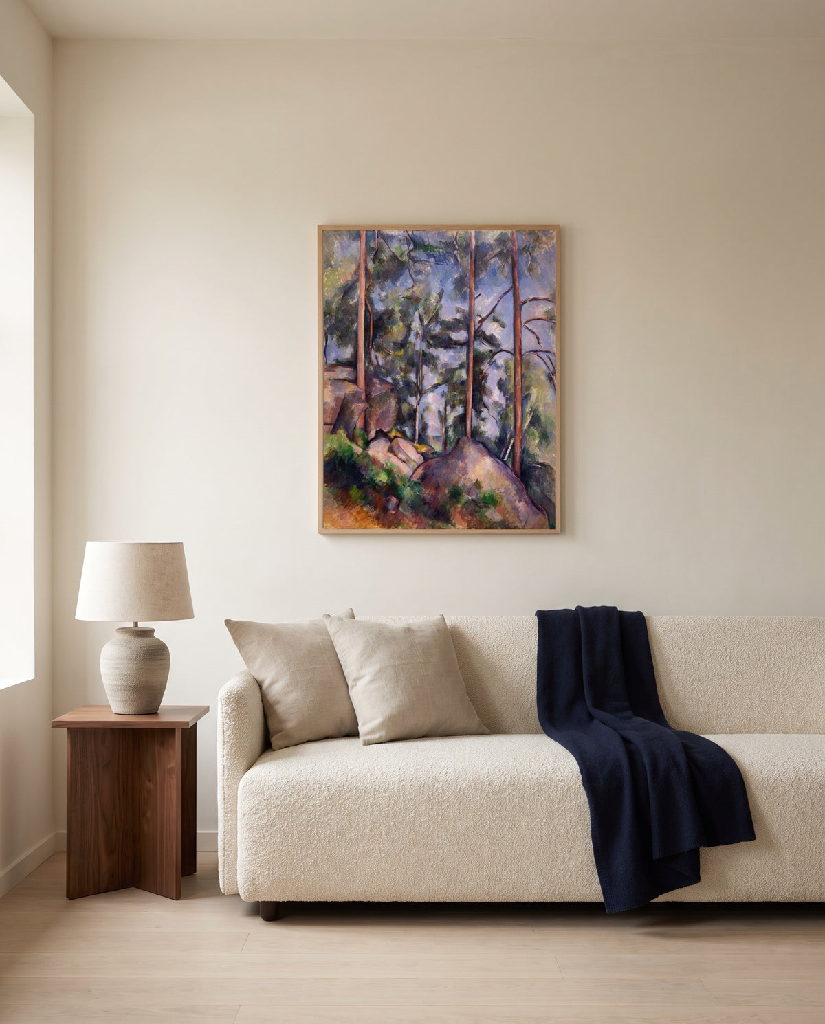Pines and Rocks by Paul Cézanne framed in natural oak above a cream sofa in a warm living room