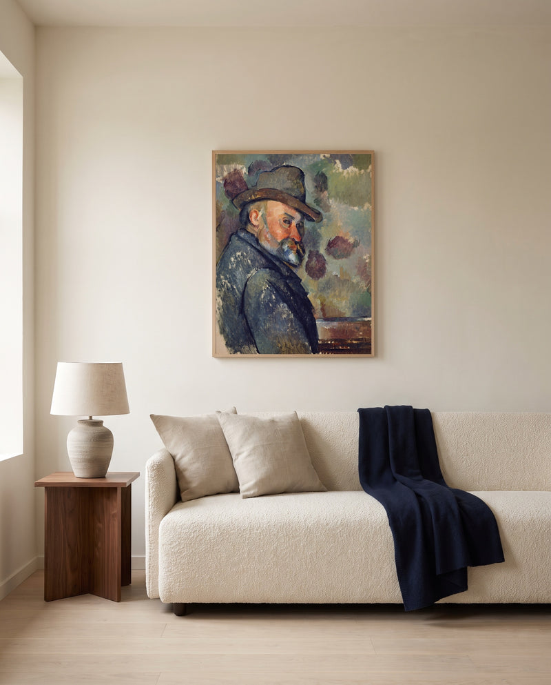 Self-Portrait with a Hat by Paul Cézanne framed in natural oak above a cream sofa in a warm living room