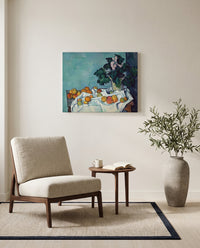 Apples and Primroses by Paul Cézanne as a stretched canvas above a linen lounge chair in a reading corner