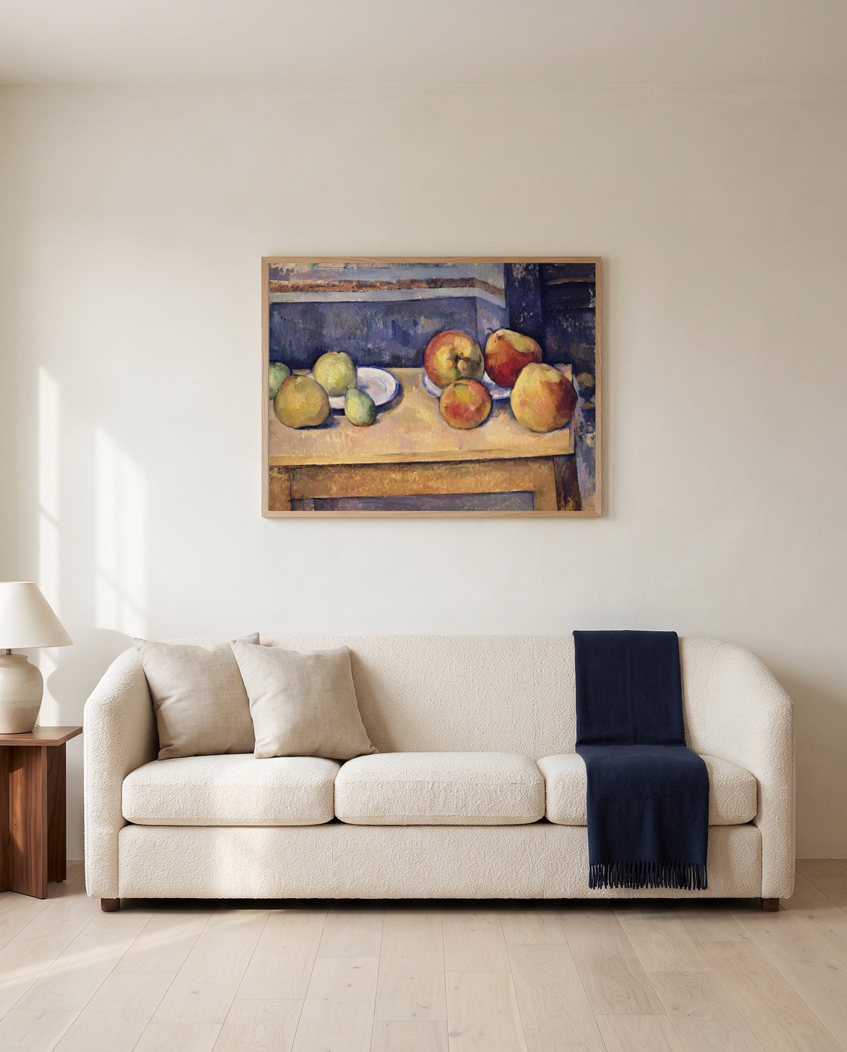 Apples and Pears by Paul Cézanne framed in natural oak above a cream sofa in a warm living room